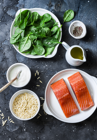 Ingredients for a balanced lunch - salmon fish, spinach, cream, orzo pasta on a dark background, top viewの写真素材