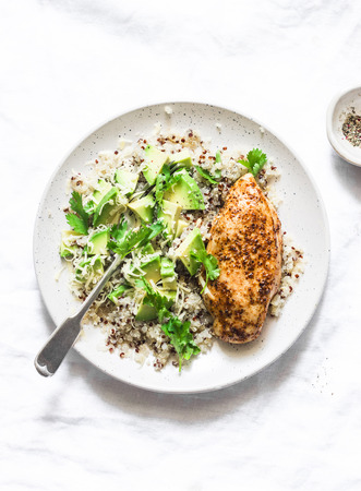 Quinoa, baked chicken breast, avocado, cheese, cilantro bowl on light background, top view. Healthy eating conceptの写真素材