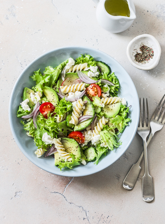 Mediterranean pasta avocado salad on a light background, top view. Vegetarian diet food conceptの写真素材