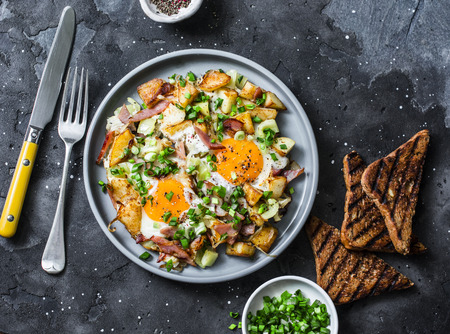 Potatoes, ham, eggs breakfast hash on a dark background, top view. Delicious, nutritious breakfast, snackの写真素材