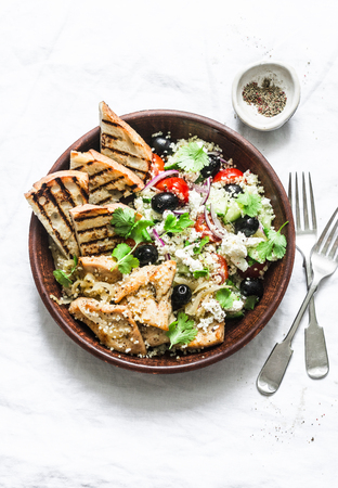 Mediterranean style lunch - couscous, cherry tomatoes, cucumbers, feta cheese, olives salad and lemon herbs roasted chicken breast on light background, top viewの写真素材
