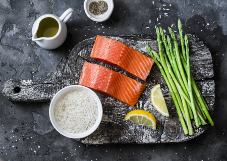 Ingredients for lunch - fresh raw organic salmon, green asparagus and rice on a dark background, top viewの写真素材