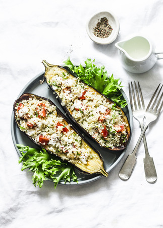 Baked eggplant stuffed with couscous, tomatoes, cilantro with yogurt sauce on a light background, top viewの写真素材