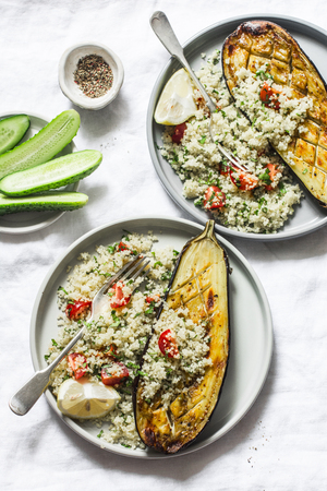 Grilled eggplant with couscous, tomatoes, cilantro with on a light background, top view. Delicious vegetarian lunch. Mediterranean style foodの写真素材