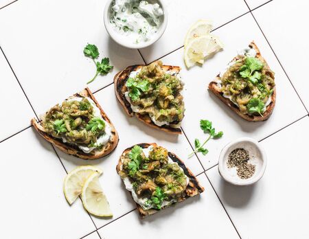 Smashed grilled eggplant bruschetta with yogurt herbs sauce - delicious appetizers, snacks, tapas on light background, top viewの写真素材