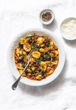 Potato turmeric gnocchi with bolognese sauce and spinach on a light background, top viewの写真素材