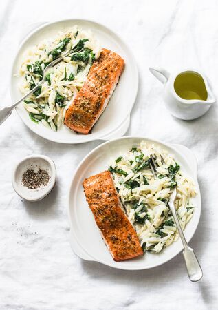 Healthy balanced lunch - creamy spinach orzotto and baked salmon on a light background, top viewの写真素材