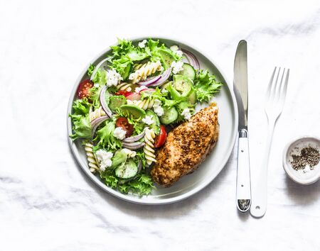 Mediterranean avocado pasta salad and baked chicken breast - healthy balanced lunch on a light background, top viewの写真素材