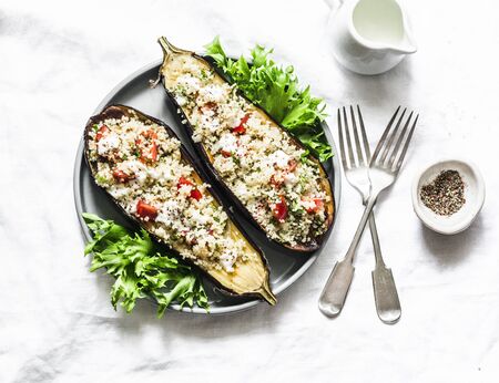 Baked eggplant stuffed with couscous, tomatoes, cilantro with yogurt sauce on a light background, top viewの写真素材