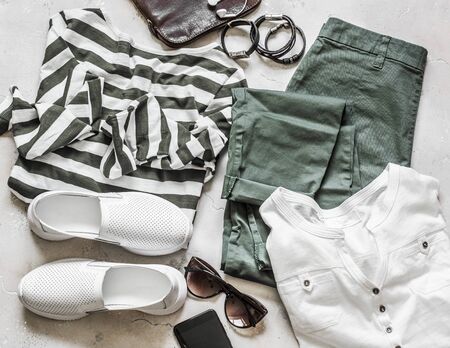 Spring summer set of women's casual wear - cotton pants, white t-shirt, striped pullover, leather sneakers, bag, smartphone and accessories on a light background, top view. Fashion conceptの写真素材