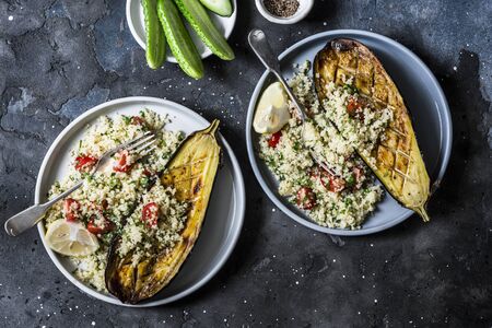 Grilled eggplant with couscous, tomatoes, cilantro with on a dark background, top view. Delicious vegetarian lunch. Mediterranean style foodの写真素材