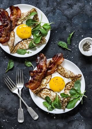 Stuffed egg crepes with bacon and arugula - delicious nutritious brunch on a dark background, top view. Flat layの写真素材