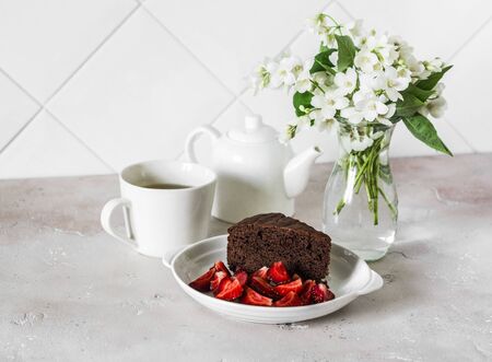 Piece of chocolate cake, strawberries and green tea on a light background. Delicious breakfast or snackの写真素材