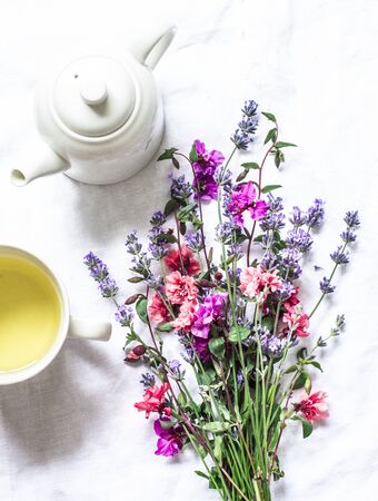 Green tea and a bouquet of garden summer flowers on a light background, top view. Flat layの写真素材
