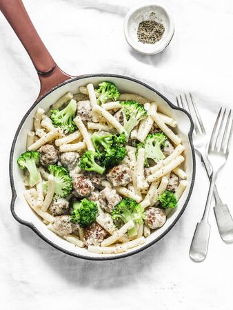 Creamy meatballs, broccoli pasta in a frying pan on a light background, top viewの写真素材