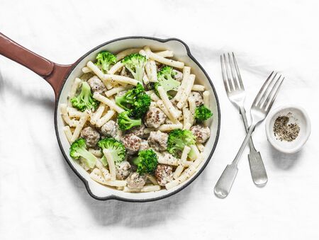 Creamy meatballs, broccoli pasta in a frying pan on a light background, top viewの写真素材