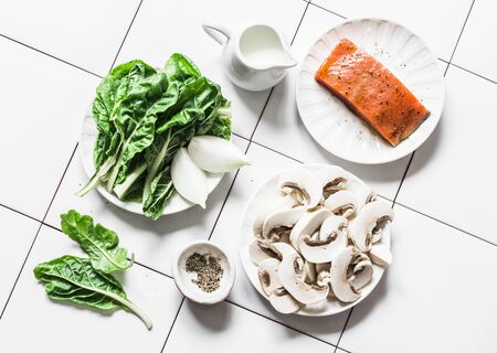 Raw ingredients for cooking salmon with creamy spinach mushrooms sauce on a light background, top view. Salmon florentine lunch. Spinach, mushrooms and salmon fishの写真素材