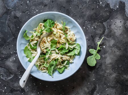 Roasted cauliflower, orzo pasta, arugula salad on a dark background, top view. Delicious vegetarian food conceptの写真素材