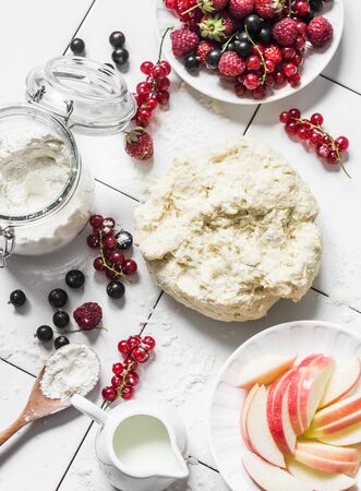 Ingredients for summer berry pie - dough, fresh ripe currant berries, raspberries, strawberries on a light background, top viewの写真素材