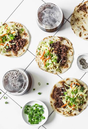 Spicy beef, coleslaw tacos and dark beer on light background, top viewの写真素材
