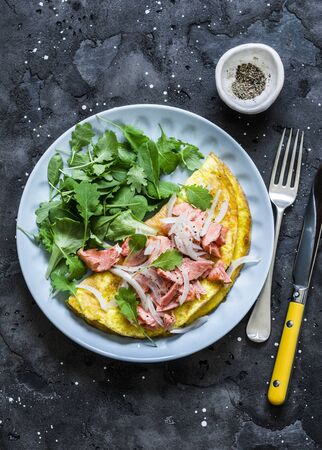 Omelet with green salad and baked salmon on a dark background, top view. Healthy breakfast, snackの写真素材