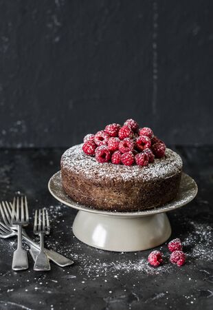 Simple chocolate cake with fresh raspberry on dark background. Delicious dessertの写真素材