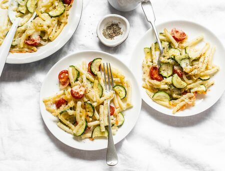 Roasted zucchini and cherry tomatoes baked mac and cheese  on the light background, top view. Vegetarian healthy lunchの写真素材