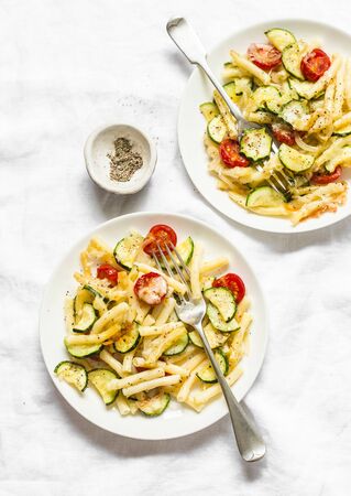 Roasted zucchini and cherry tomatoes baked mac and cheese  on the light background, top view. Vegetarian healthy lunchの写真素材