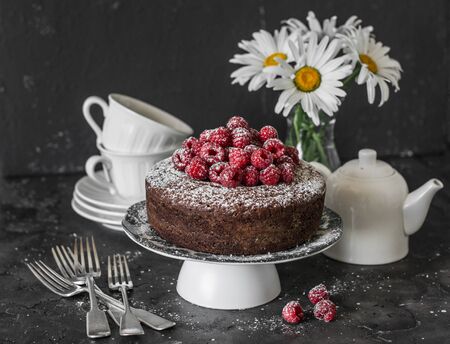 Served tea table still life - chocolate nut cake with raspberry on a dark background. Delicious dessert.Flat layの写真素材