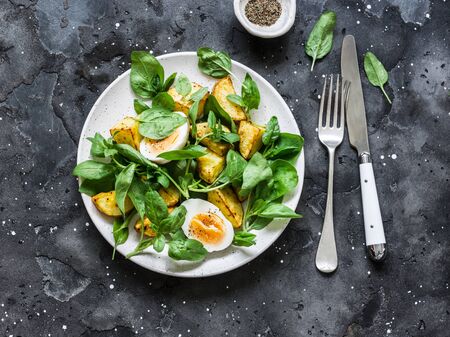 Baked potato, boiled egg and spinach salad on dark background, top viewの写真素材