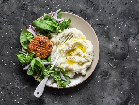Chicken cutlet with cauliflower puree and fresh spinach on dark background, top viewの写真素材