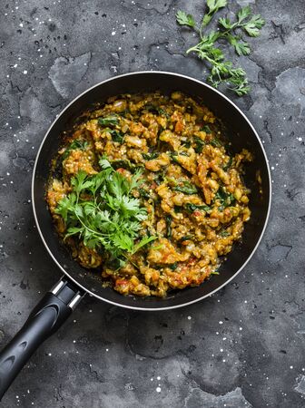 Eggplant spinach vegetarian curry in a pan on a dark background, top view. Indian cuisineの写真素材