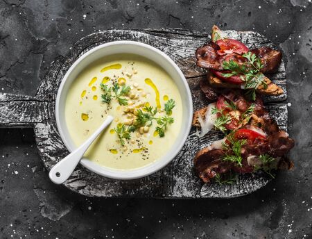 Sweet corn mashed soup with bacon tomato parmesan whole grain bread toast on dark background, top viewの写真素材
