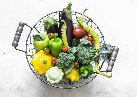 Fresh organic farm vegetables - broccoli, eggplant, pepper, tomatoes, squash in a basket on a light background, top view. Healthy diet food conceptの写真素材