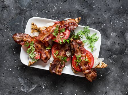 Bacon, tomatoes, parmesan, whole grain bread sandwiches on a dark background, top viewの写真素材