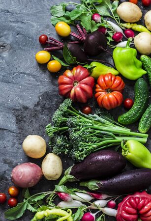 Fresh seasonal vegetables food background. Aubergines, tomatoes, radishes, peppers, broccoli, potatoes, beets on a dark background, top view. Flat layの写真素材