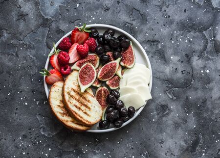Snack appetizers tapas plate with cheese, figs, olives, berries on a dark background, top viewの写真素材