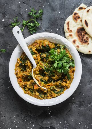 Aubergine spinach vegetarian curry with naan flatbread on a dark background, top view. Indian cuisineの写真素材