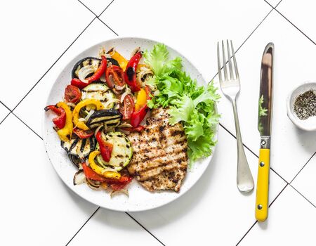 Grilled flounder fillet and roasted vegetables on a light background, top view. Delicious healthy diet foodの写真素材