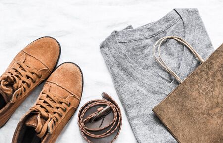 Sale purchase concept. Women's grey pullover, suede brown boots, leather belt and paper bag on light background, top viewの写真素材