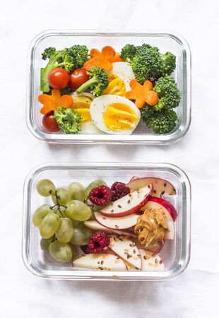 Healthy diet snack, breakfast lunch box on light background, top view. Boiled egg, fresh vegetables and fruits - tasty healthy food conceptの写真素材
