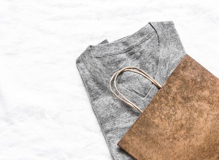Female gray sweater and paper bag on a light background, top view. Copy space, sale shopping conceptの写真素材