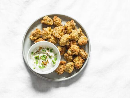 Baked crispy parmesan bread crumbs cauliflower bites with yogurt sauce on lightl background, top viewの写真素材