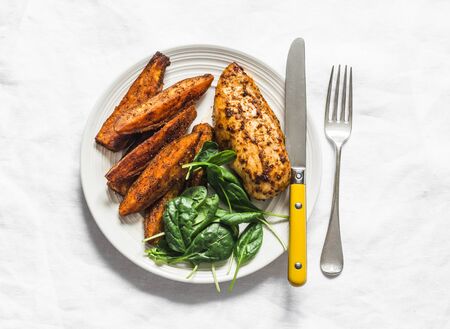 Baked chicken breast with sweet potatoes and spinach on a light background, top view. Balanced healthy lunchの写真素材