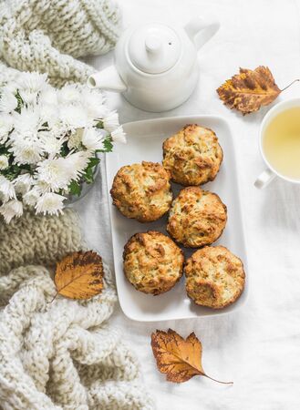 Caramelized cinnamon apples muffins, green tea, bouquet of chrysanthemums, knitted plaid on a light background, top view. Cozy dessertの写真素材