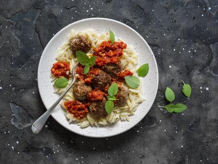 Orzo pasta with meatballs and tomato sauce on dark background, top viewの写真素材