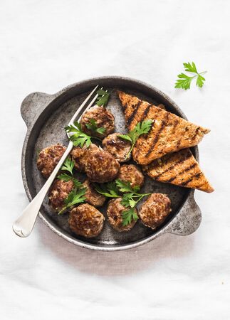 Fried meatballs in a frying pan on a light background, top viewの写真素材