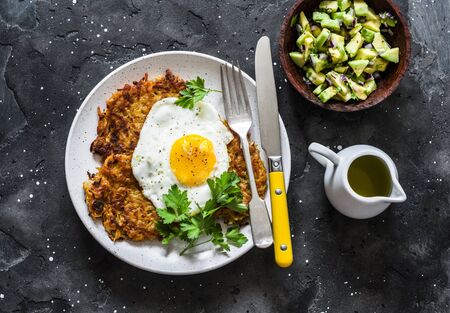 Sweet potato rostis with fried egg and avocado salsa on dark background, top viewの写真素材