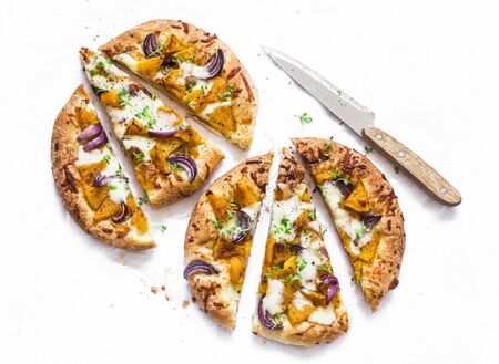 Cheesy autumn veggie flatbread. Pumpkin, sweet potato, red onion, mozzarella pizza on light background, top viewの写真素材