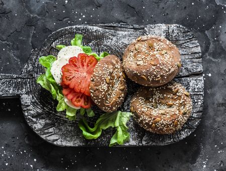 Multigrain multiseed fitness buns and green salad tomato homemade cheese sandwich on dark background, top view. Healthy diet food conceptの写真素材